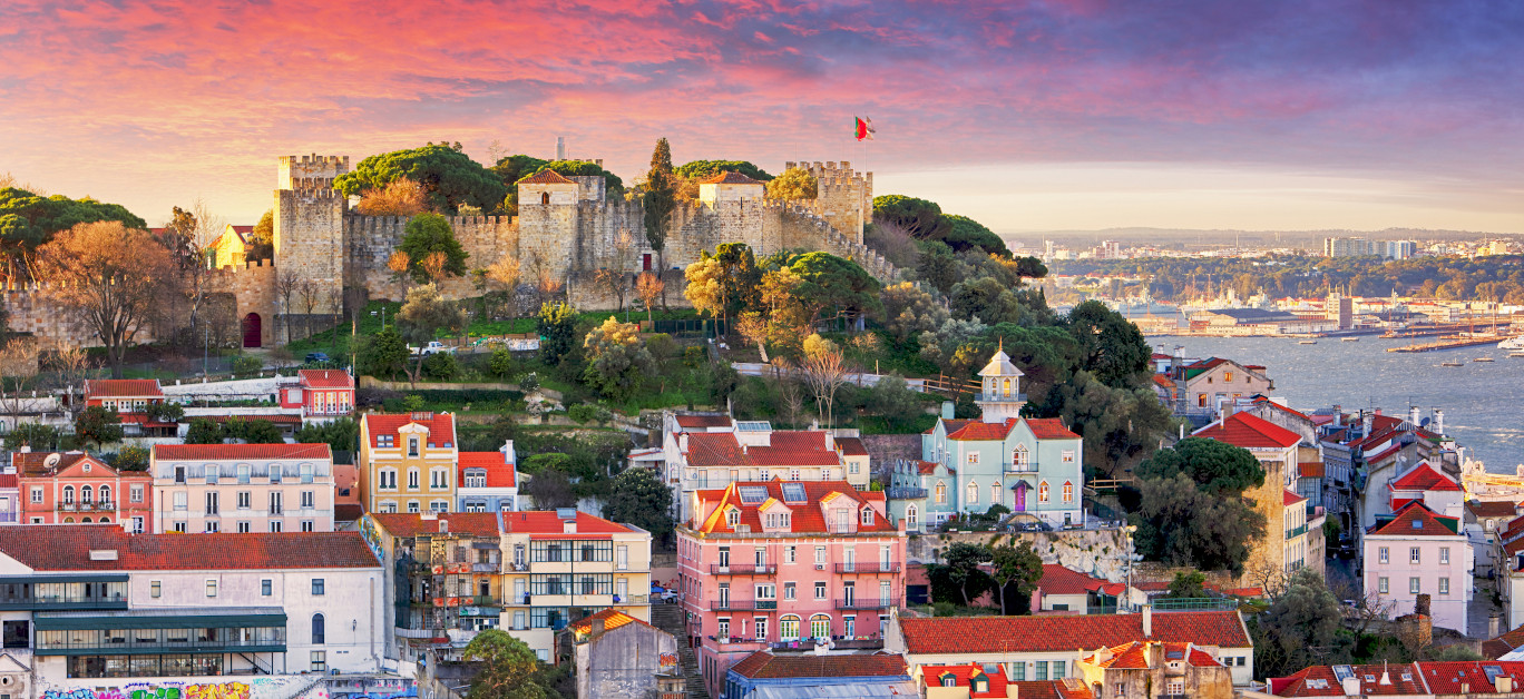 Sunset over Lisbon, with São Jorge Castle above the city rooftops and the Tagus river beyond